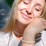 Woman wearing pearl necklaces and bracelet with a blurred background