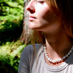 Woman wearing a pearl necklace in a natural setting