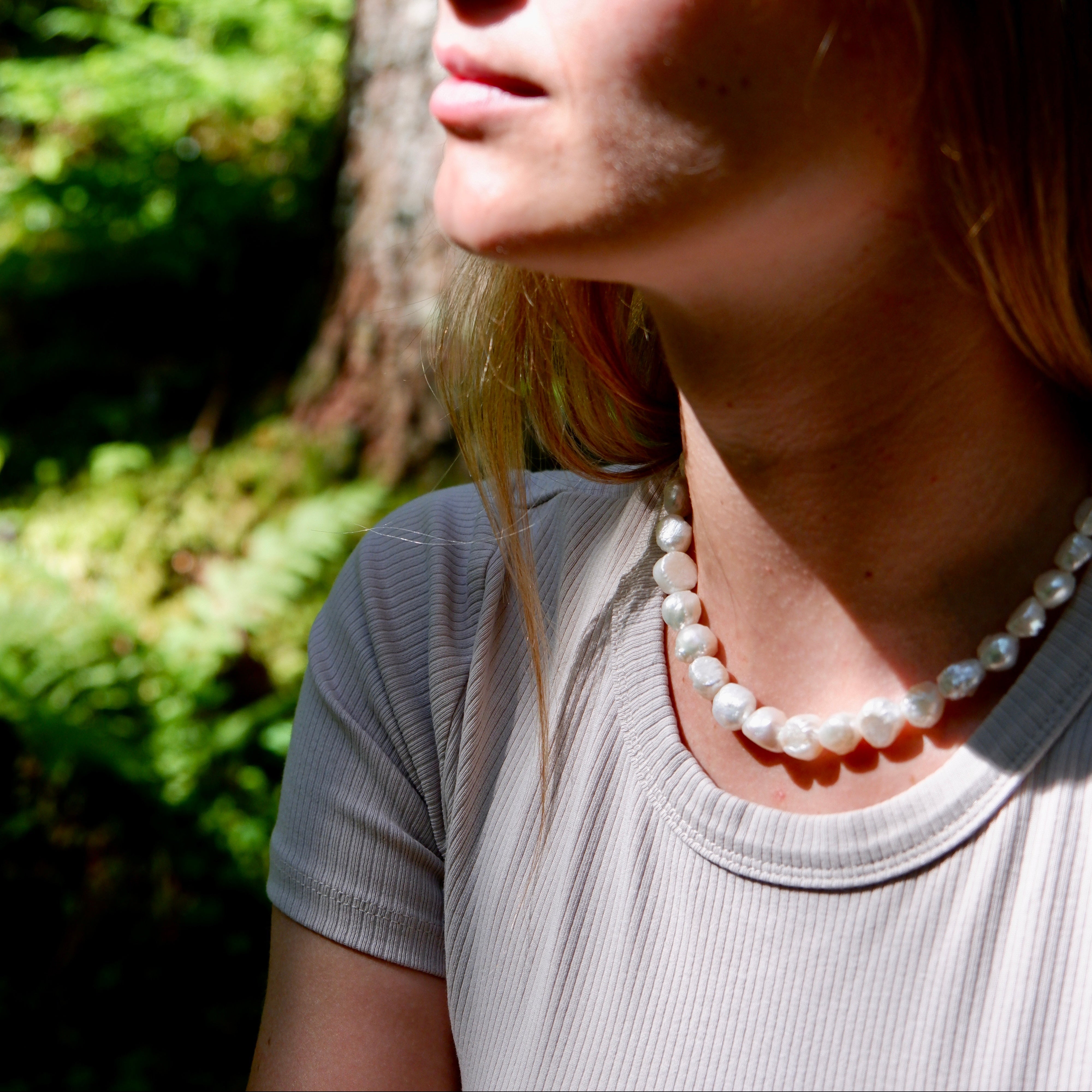 Woman wearing a pearl necklace in a natural setting