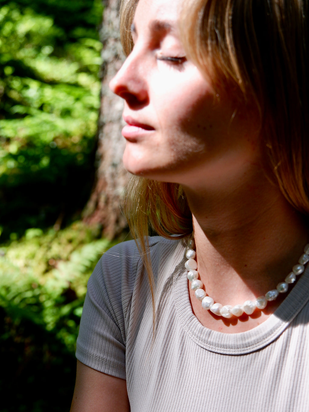 Woman wearing a pearl necklace in a natural setting