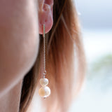 Close-up of a person wearing pearl earrings with a blurred background