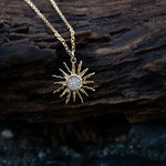 Gold sun-shaped pendant necklace on a wooden surface